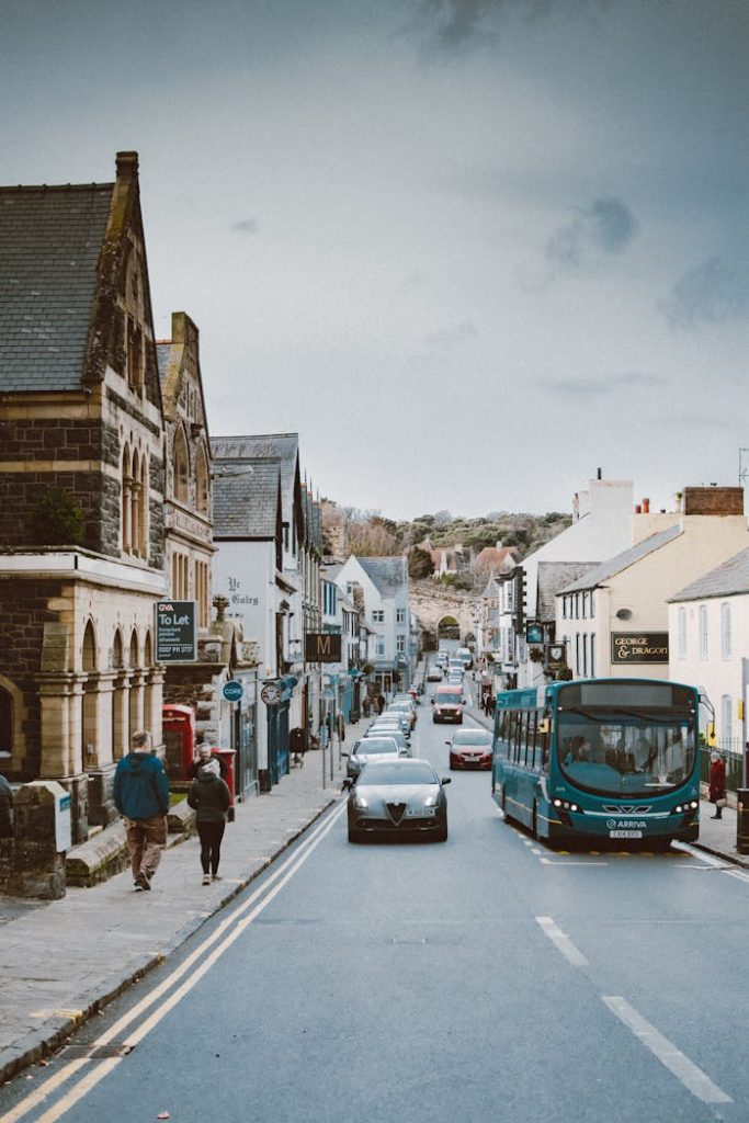 photo-of-town-during-daytime-3353612 A bustling street in Conwy, Wales with cars, bus, and pedestrians on a cloudy winter day.